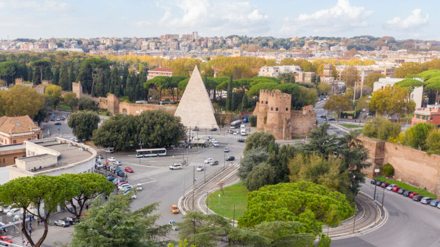 Ostiense Square in Testaccio, Rome, featuring the Pyramid of Cestius in the background against a clear blue sky