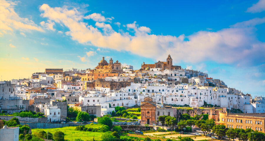 Skyline of Ostuni at sunset, showcasing white buildings against a colorful sky in Brindisi, Apulia, Italy.