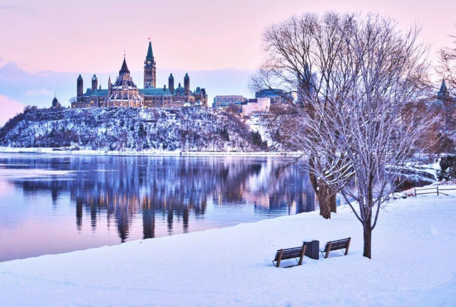 Winter view of Canada’s Parliament Buildings in Ottawa with snow and reflections.