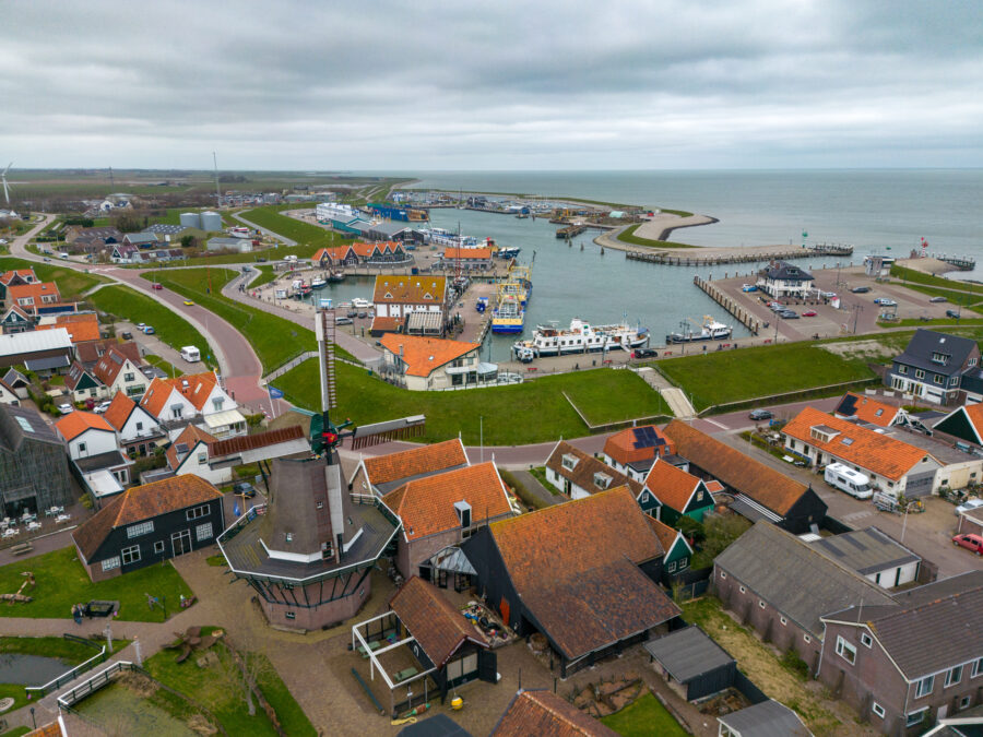 Aerial view of Oudeschild, a coastal town in Texel, featuring a busy port with multiple ships on the Wadden Sea.