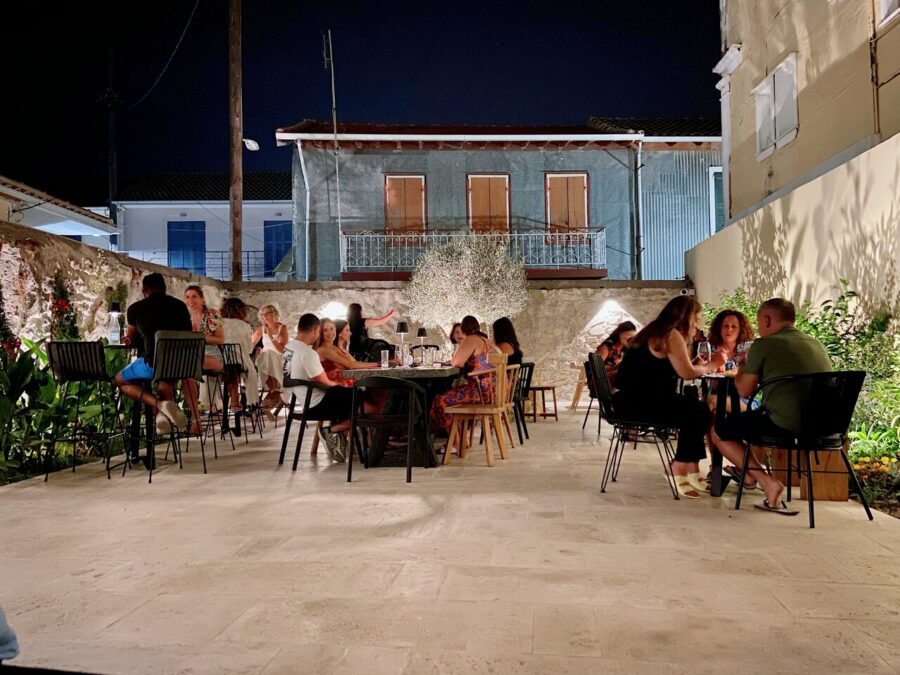 Outdoor dining scene in Lefkada Town courtyard featuring charming architecture and lively interaction.