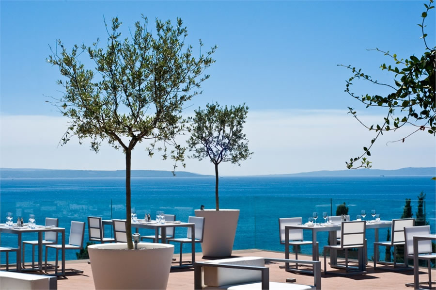 Serene coastal restaurant terrace with elegant dining setup and ocean views.