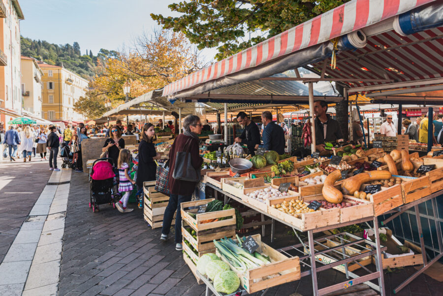 Bustling market with fresh produce, vibrant community, scenic backdrop, and historical architecture.
