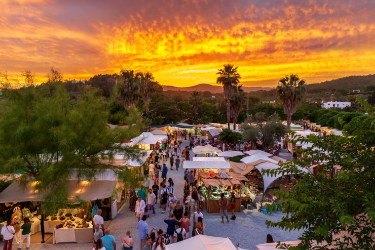 Vibrant sunset market scene with handmade crafts, lively crowd, and scenic backdrop.
