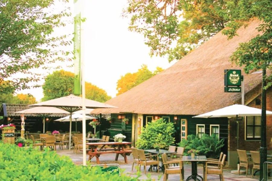 Giethoorn thatched-roof cafe patio with outdoor seating and umbrellas.