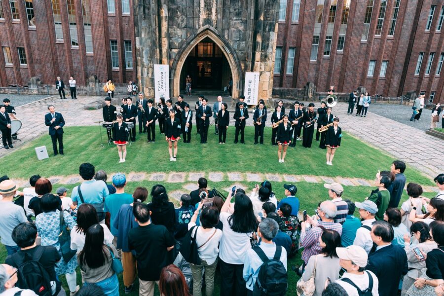 University outdoor performance with diverse crowd and historical architecture.