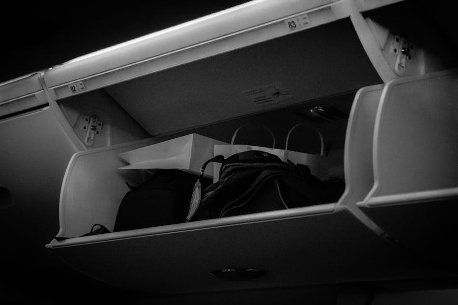 Airplane overhead cabin storage with bags and box, organized travel essentials.