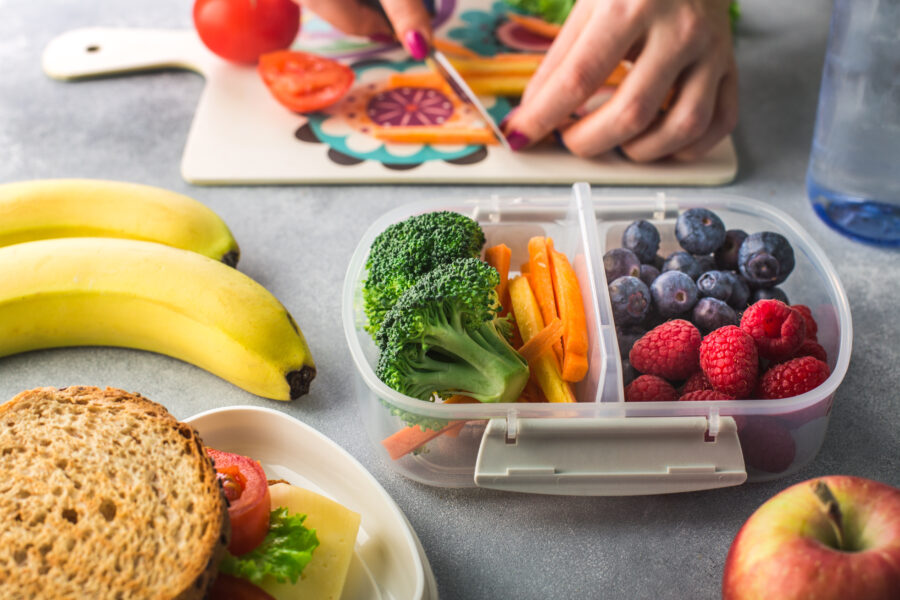 Preparing a healthy lunch in the morning, featuring fresh vegetables and whole grains in a lunchbox.