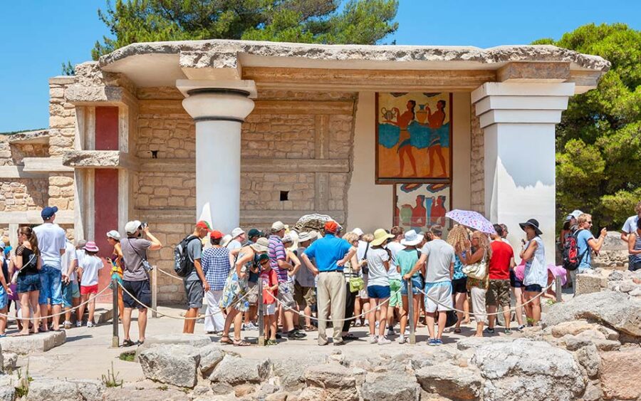 Tourists explore vibrant ruins at the Palace of Knossos, Crete, Greece.