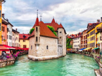 Scenic view of Annecy's Old Town with the Palais de l'Île situated in the Thiou canal, highlighting medieval village charm.