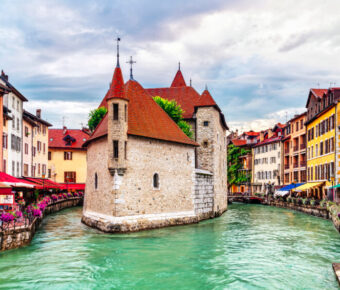 Scenic view of Annecy's Old Town with the Palais de l'Île situated in the Thiou canal, highlighting medieval village charm.