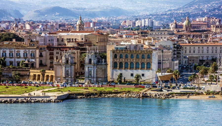 Sunset over the Mediterranean Sea, showcasing Palermo's old city with warm hues reflecting on the water