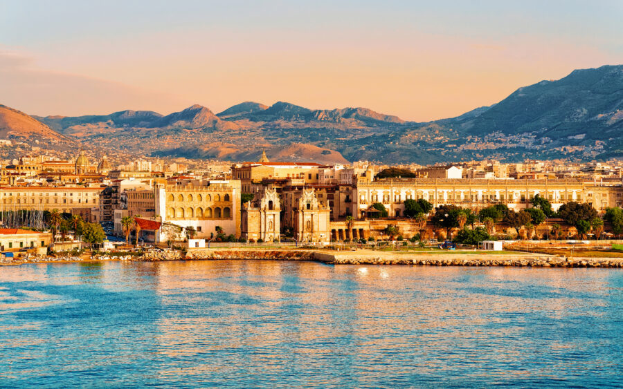 Sunset over the Mediterranean Sea, showcasing Palermo's old city with warm hues reflecting on the water