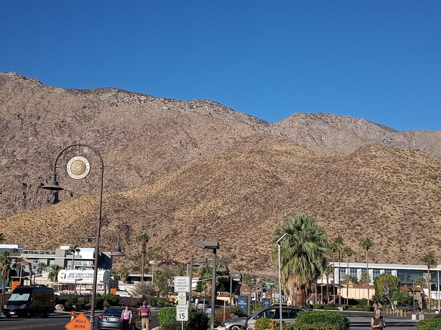 Palm Springs street scene with a clock tower centrally located amidst the arid desert surroundings.
