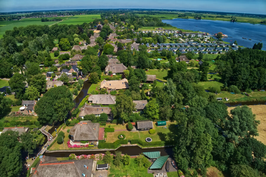 Aerial view of Giethoorn village, showcasing its canals, thatched-roof houses, and lush greenery in the Netherlands.