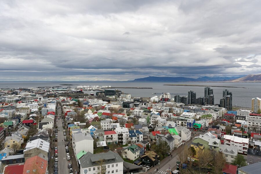 Panoramic view of Reykjavík, Iceland, showcasing colorful buildings and the surrounding mountains under a clear sky.