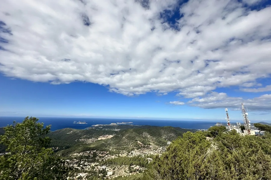 Panoramic view of lush landscape, ocean, clouds, and modern structures at Sa Talaia.