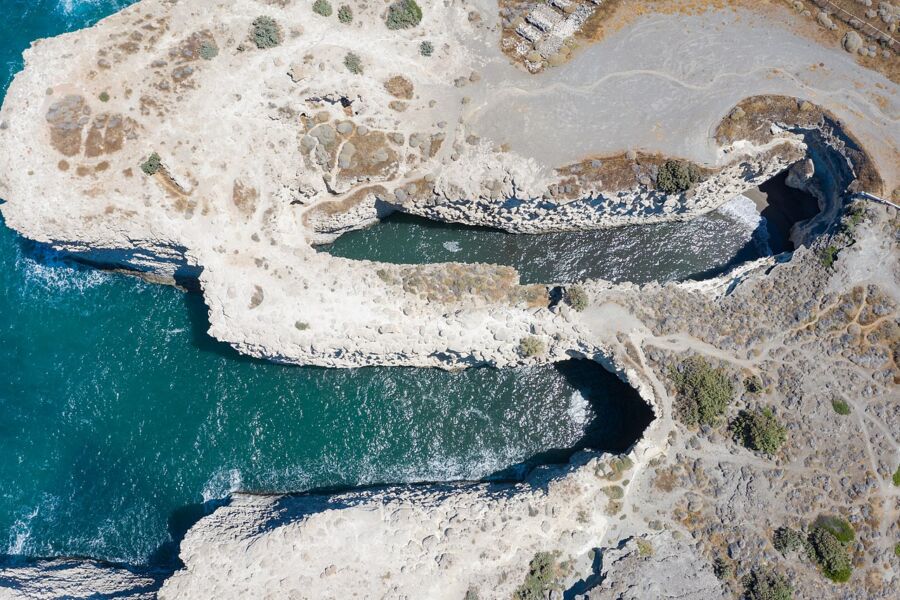 Aerial view of Papafragas Beach on Milos Island, Greece, showcasing a dramatic cliffside meeting the deep blue ocean.
