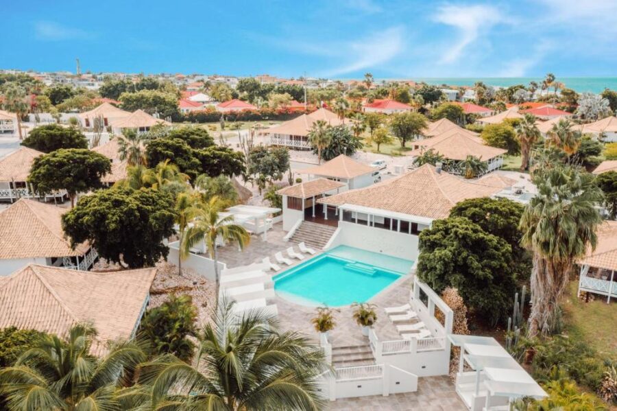 Papagayo Beach Resort in Curacao, featuring a pool surrounded by lush palm trees.
