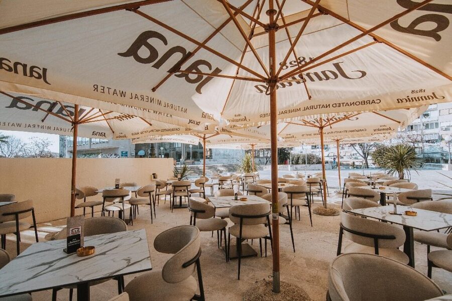 Outdoor dining area at Papa’s True American Burger Bar in Split, Croatia, featuring tables and chairs under colorful umbrellas.