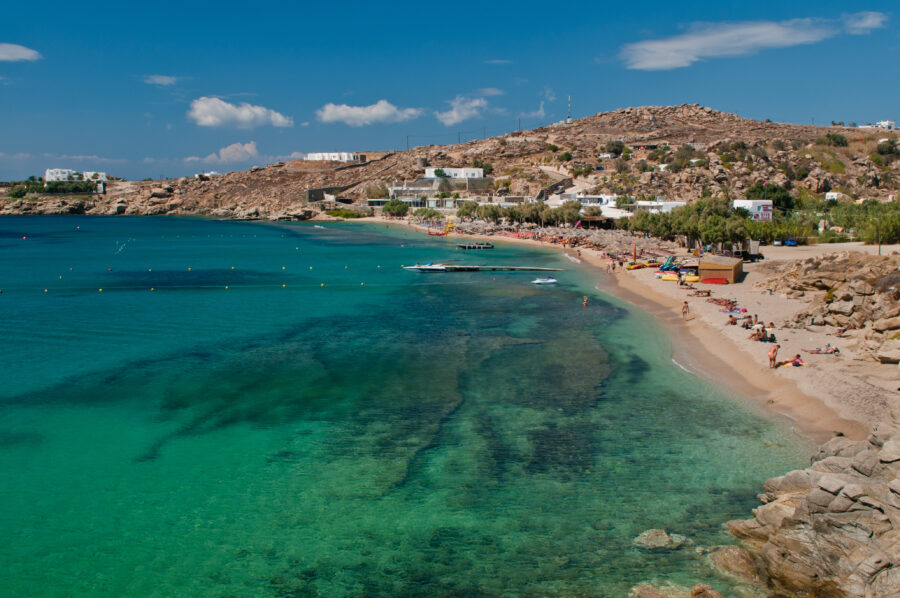 scenic view of Paradise Beach in Mykonos, Greece, featuring golden sand and clear blue waters under a sunny sky