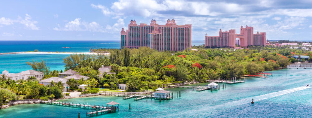 Scenic view of a white sand beach on Paradise Island, Nassau, with clear blue waters and lush tropical surroundings.