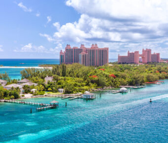Scenic view of a white sand beach on Paradise Island, Nassau, with clear blue waters and lush tropical surroundings.
