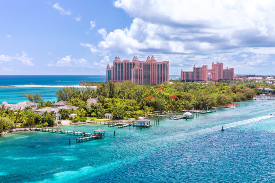 Scenic view of a white sand beach on Paradise Island, Nassau, with clear blue waters and lush tropical surroundings.