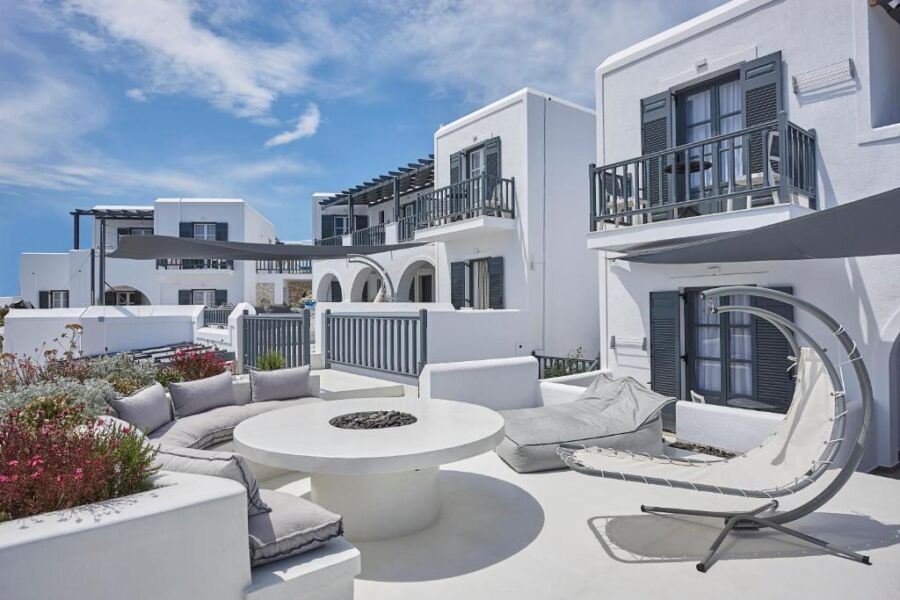 The Parian Boutique Hotel features a white house with a cozy patio and stylish furniture, perfect for relaxation in Greece.