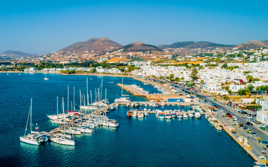 Bird's-eye view of Parikia marina, showcasing numerous sailboats anchored in the picturesque waters of Paros Island, Greece.