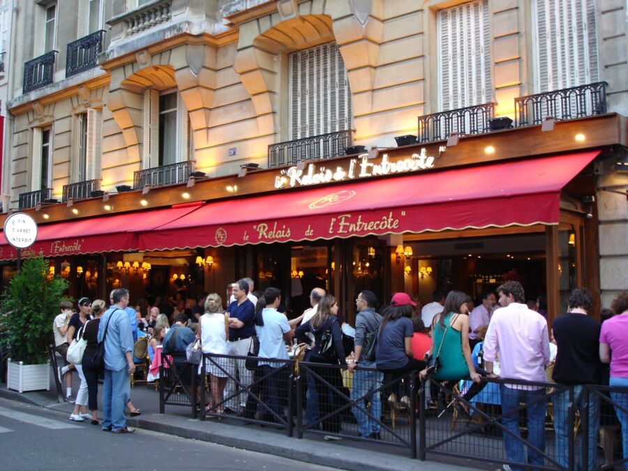 Popular Paris restaurant Le Relais de lEntrecôte with bustling outdoor dining scene.