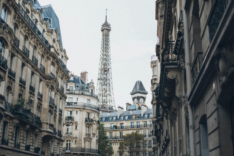 Paris street view with Eiffel Tower and Haussmannian architecture in soft morning light.