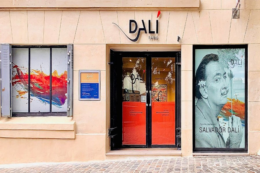 Dalí Museum Paris gallery entrance with stone façade, colorful abstract window and portrait poster.