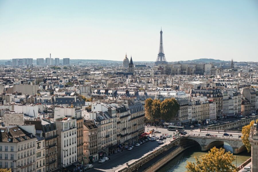 Paris skyline with Eiffel Tower, Seine River, and classic architecture under a vibrant sky.