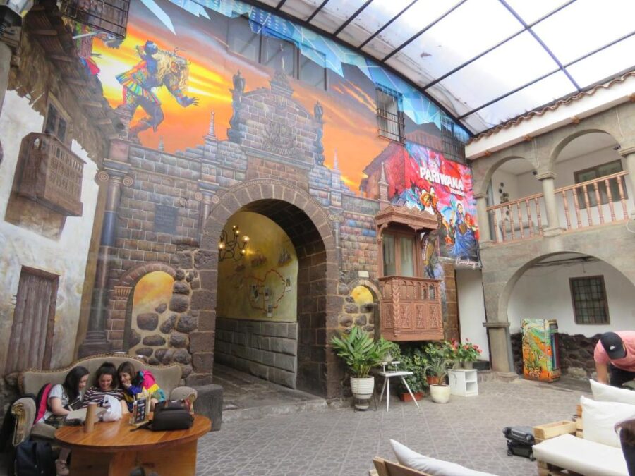 Lobby of Pariwana Hostel Cusco featuring a vibrant mural on the wall, showcasing local culture and art in Cusco, Peru.