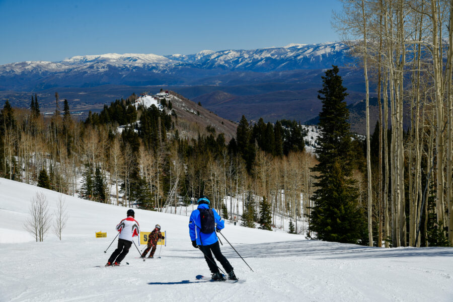 Skier enjoying a sunny day on the slopes at Park City Canyons Ski Area, surrounded by beautiful spring scenery