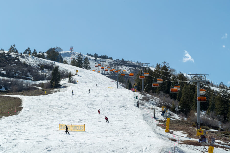 Skiers navigate the slopes at Park City Utah Ski Resort, surrounded by snow-covered mountains and clear blue skies