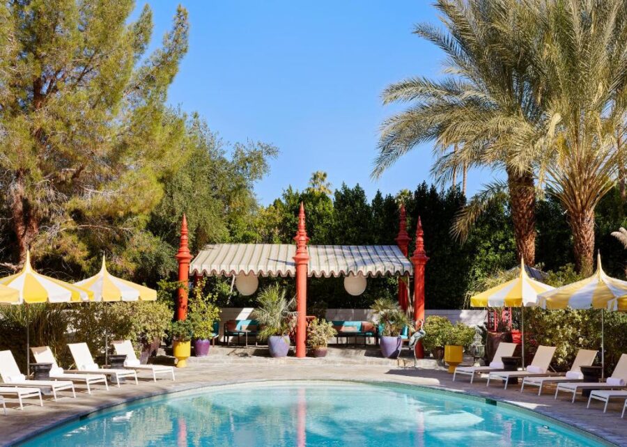 The pool at Parker Palm Springs resort, surrounded by palm trees and lounge chairs, showcasing a relaxing vacation atmosphere.

