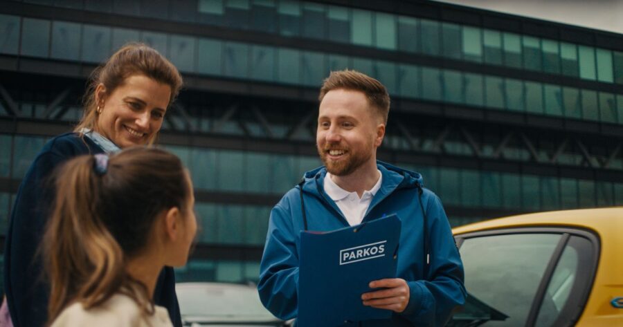 Parking attendant providing customer service to family at parking check-in with Parkos folder.