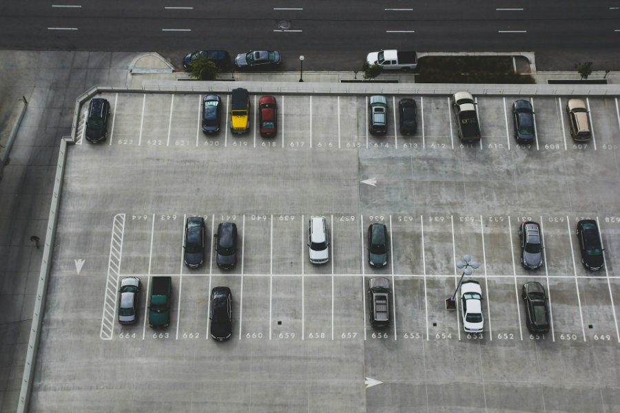 Aerial view of rooftop concrete parking deck with numbered stalls and parked cars.