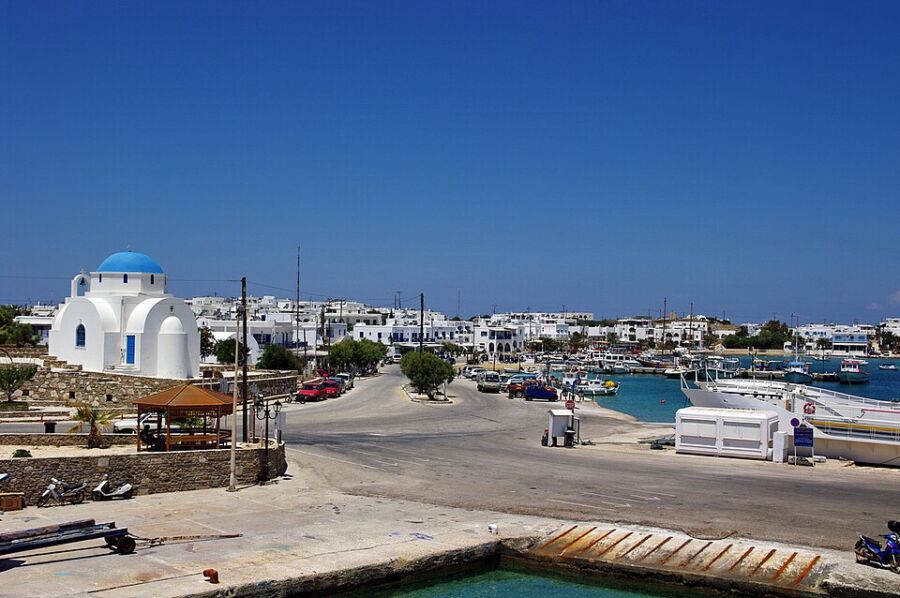 Picturesque harbor in Paros Antiparos, Greece, featuring colorful boats and a charming church in the background.