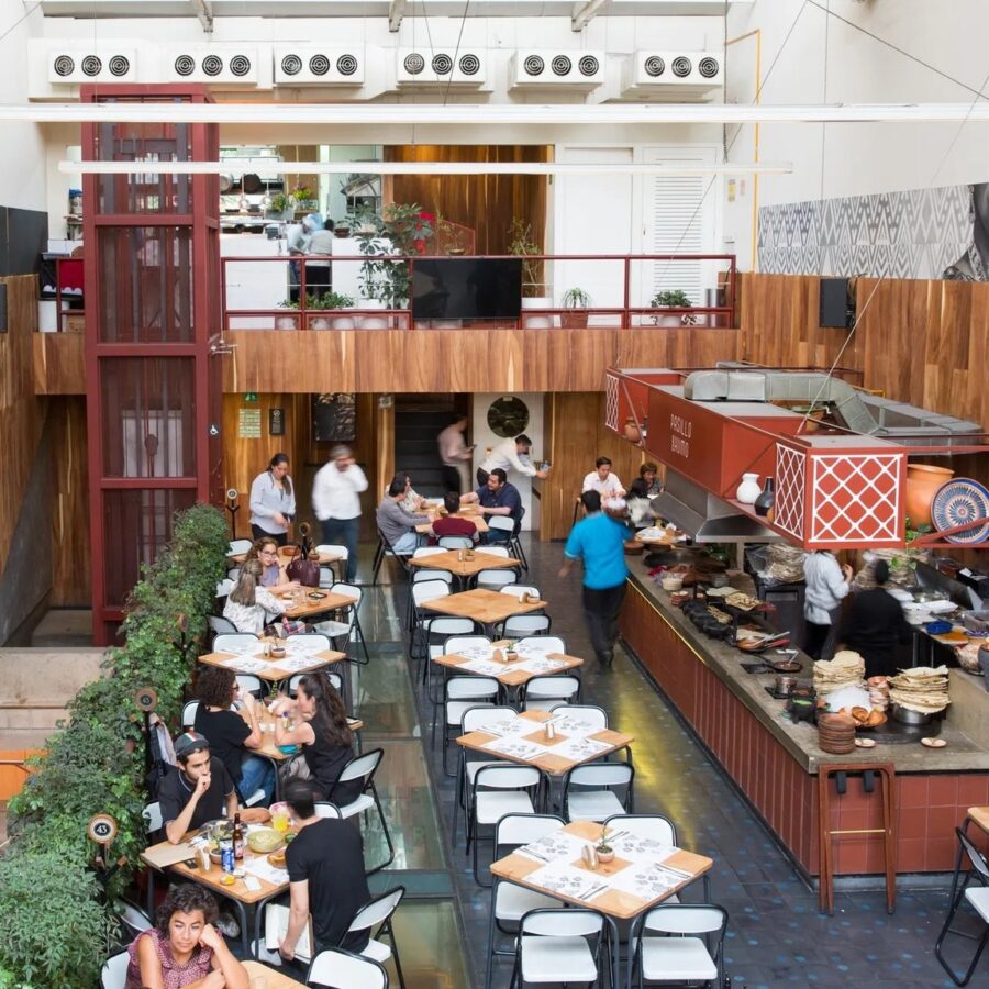 Interior of a lively restaurant in Pasillo de Humo, Mexico, showcasing numerous tables occupied by people eating.
