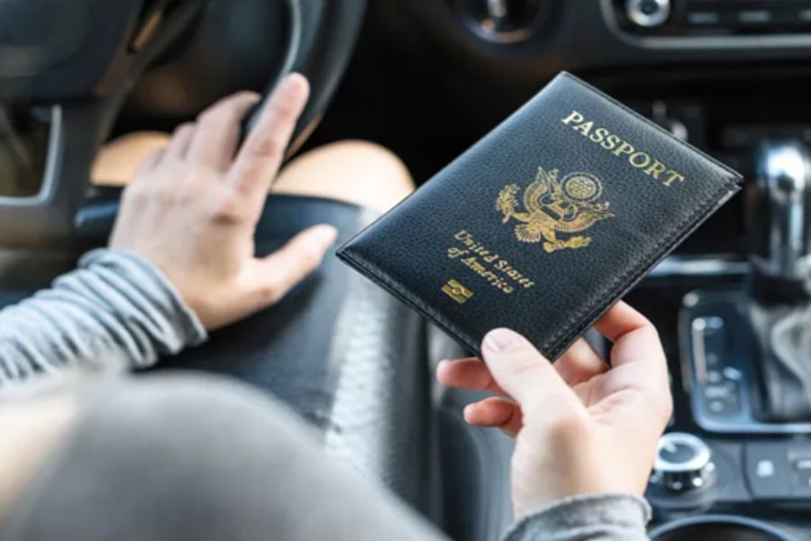 Person holding US passport in car, indicating readiness for travel and adventure.
