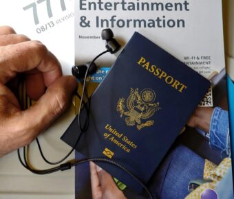 Travel preparation with US passport, earphones, and entertainment magazine on plane.
