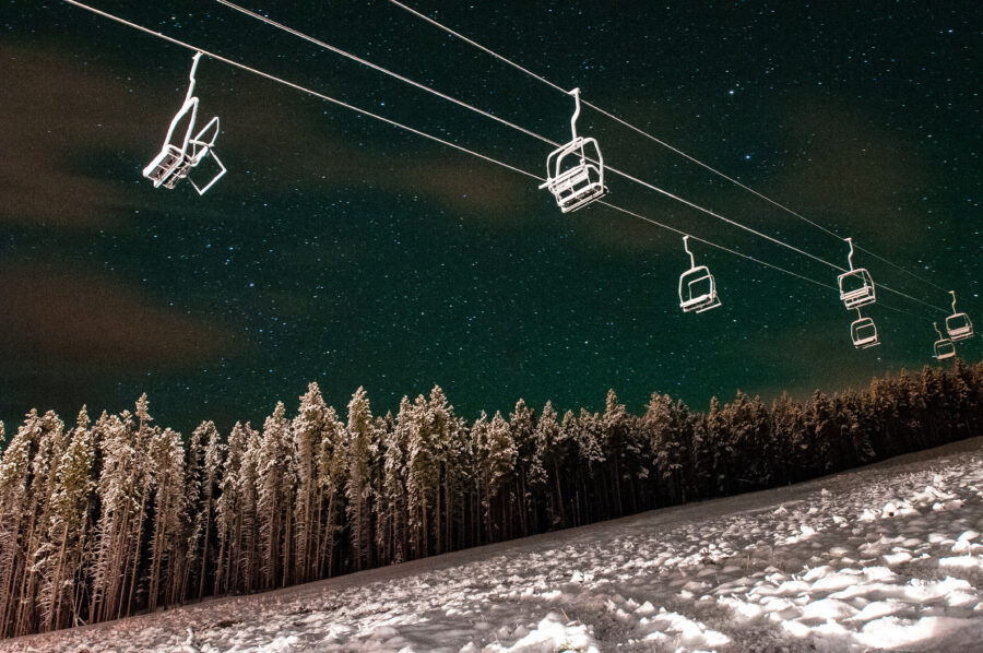 Night view of Peak 8 ski lifts in Breckenridge, Colorado, illuminated against a dark sky, showcasing winter sports ambiance