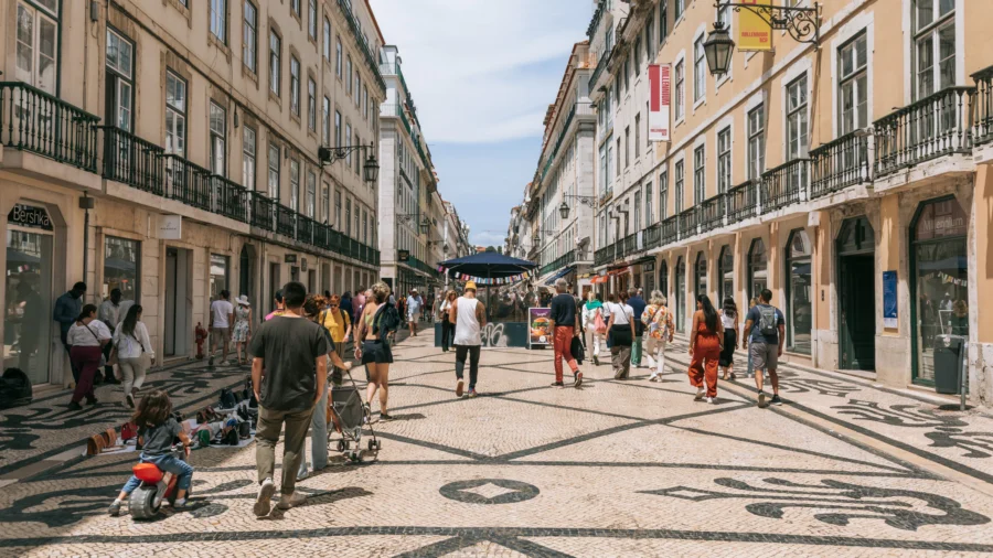 Chiado pedestrian street in Lisbon with black and white mosaic pavement and outdoor market stalls.