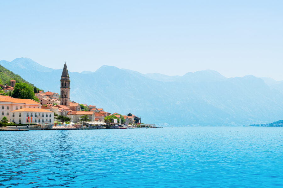 Scenic summer view of Perast, Montenegro, showcasing its historic architecture against a vibrant landscape.