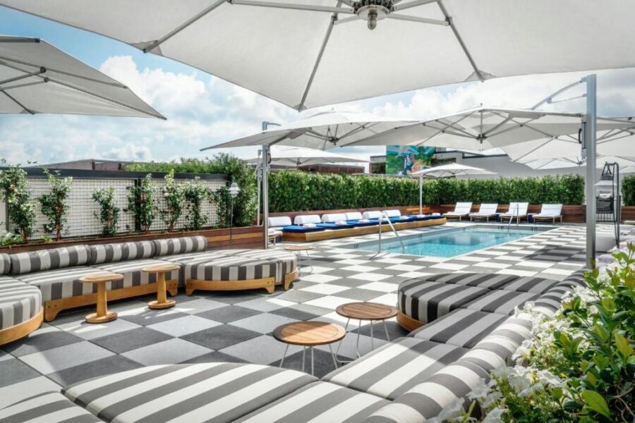 The pool area at Perry Lane Hotel features a checkered floor and white umbrellas, creating a luxurious atmosphere.
