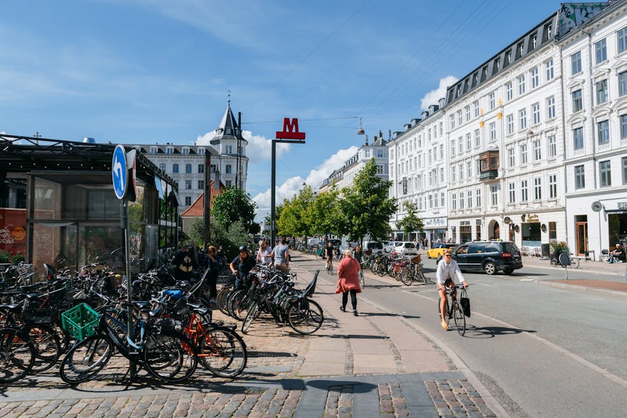 Cyclists riding along wide embankment near historic buildings in city