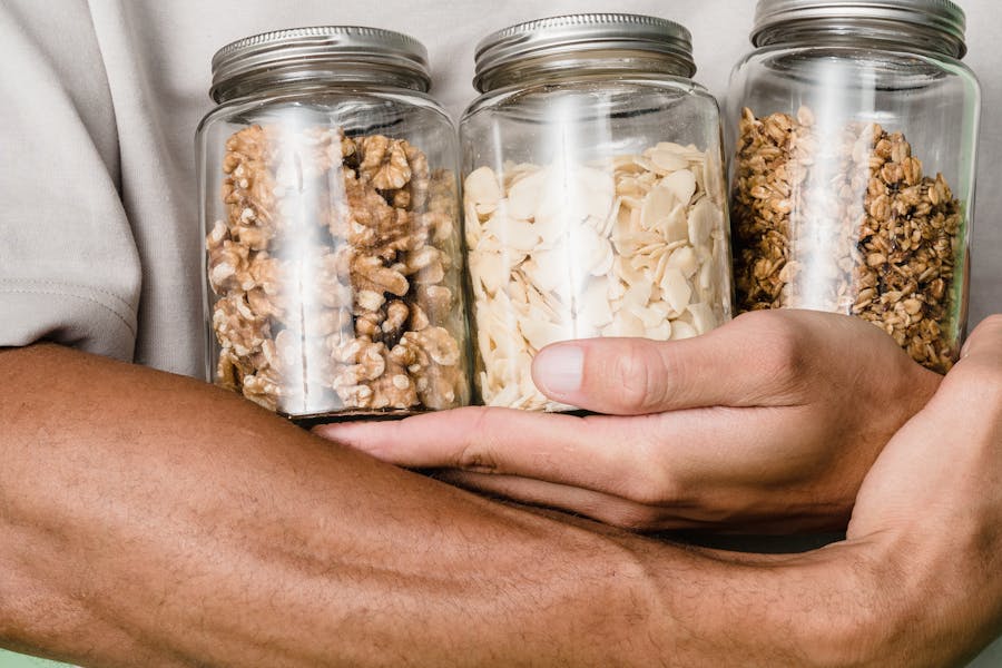Person Holding Clear Glass Jar With White and Brown Beans